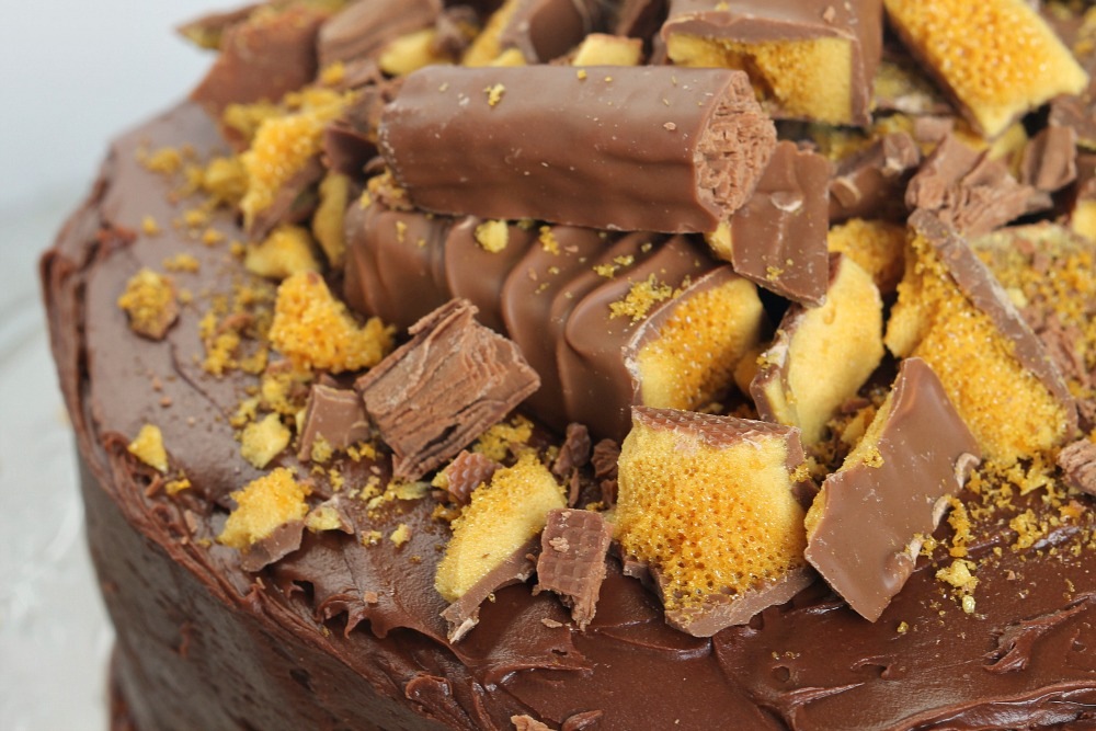 A close up of a chocolate cake with crunchie and twirl on top