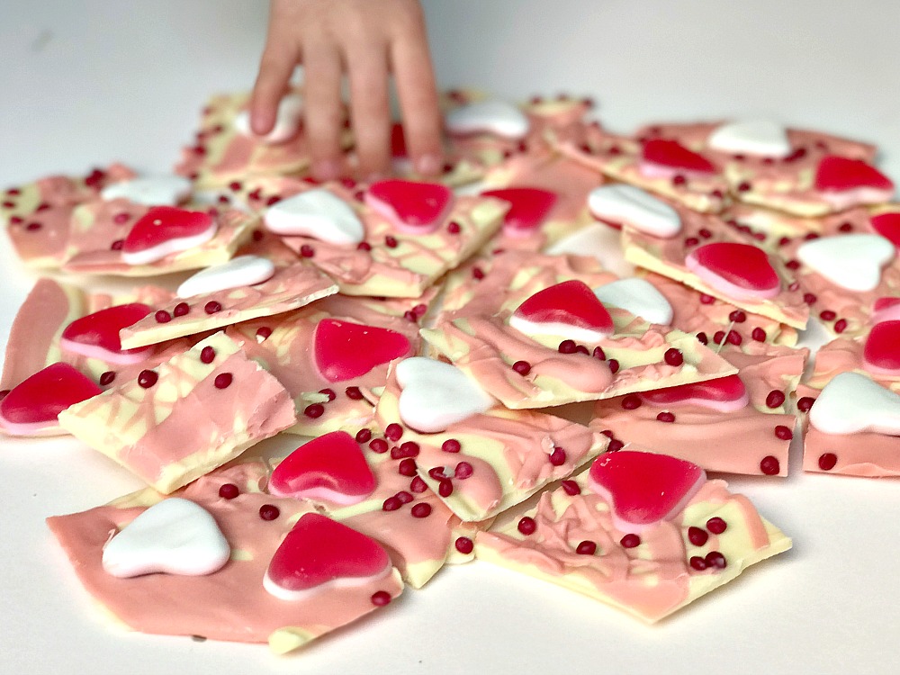 A Valentine's Day treat of chocolate bark. White and pink chocolate covered in pink hearts and sprinkles