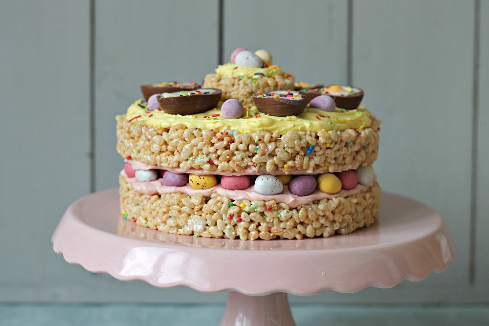 An Easter cake make out of rice crispy treats sits on a pink cake stand.
