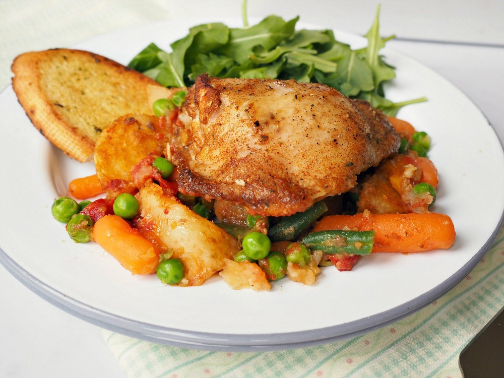 A plate with Chicken, mixed vegetables, garlic bread and a leaf salad.