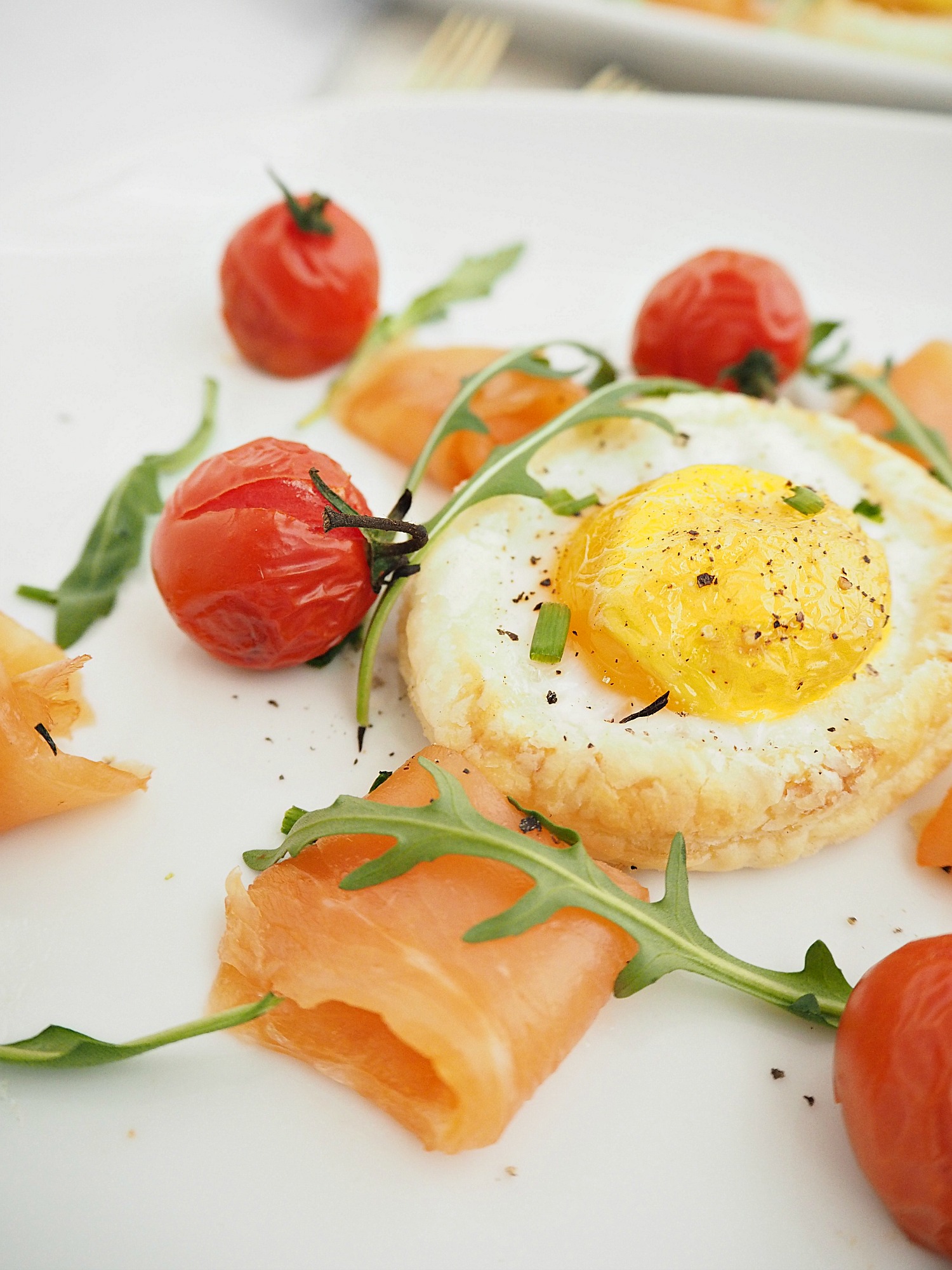 baked eggs, smoked salmon, rocket and roasted cherry tomatoes on a white plate