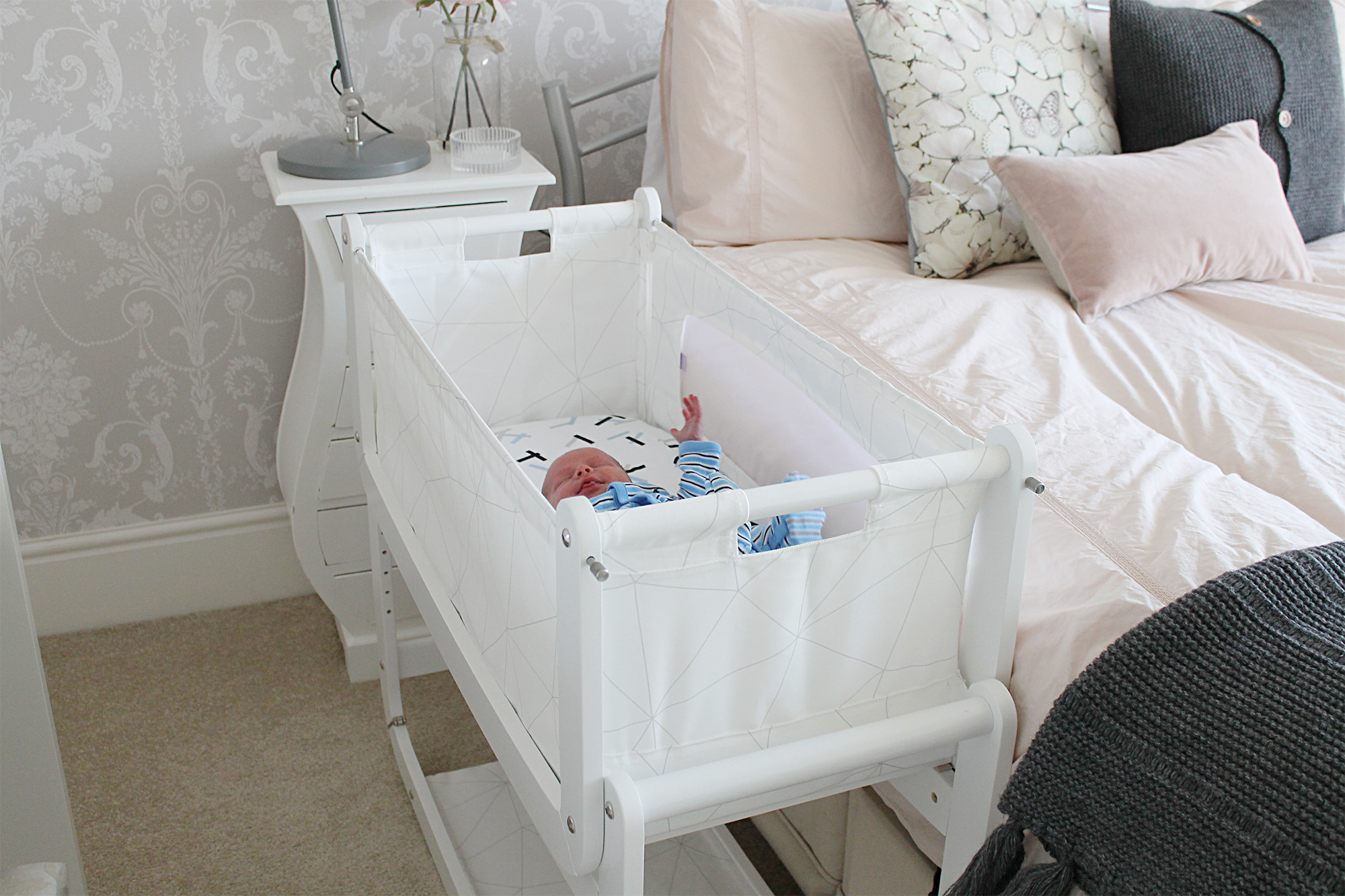 SnuzPod 3 in 1 Bedside Crib next to a bed with a newborn in it.