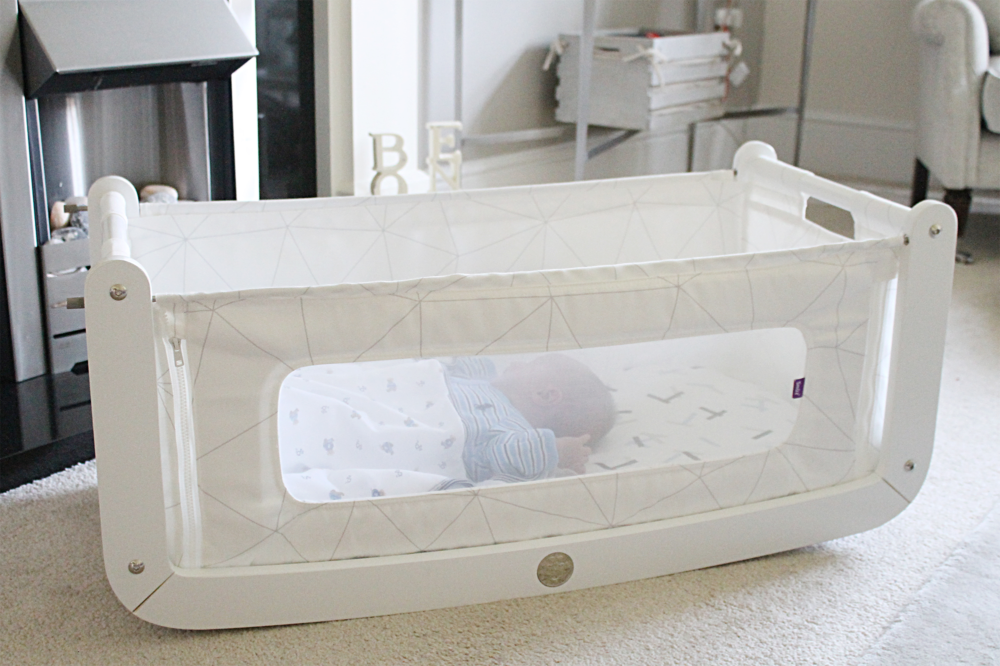 A white rocking bassinet on the floor of a living room