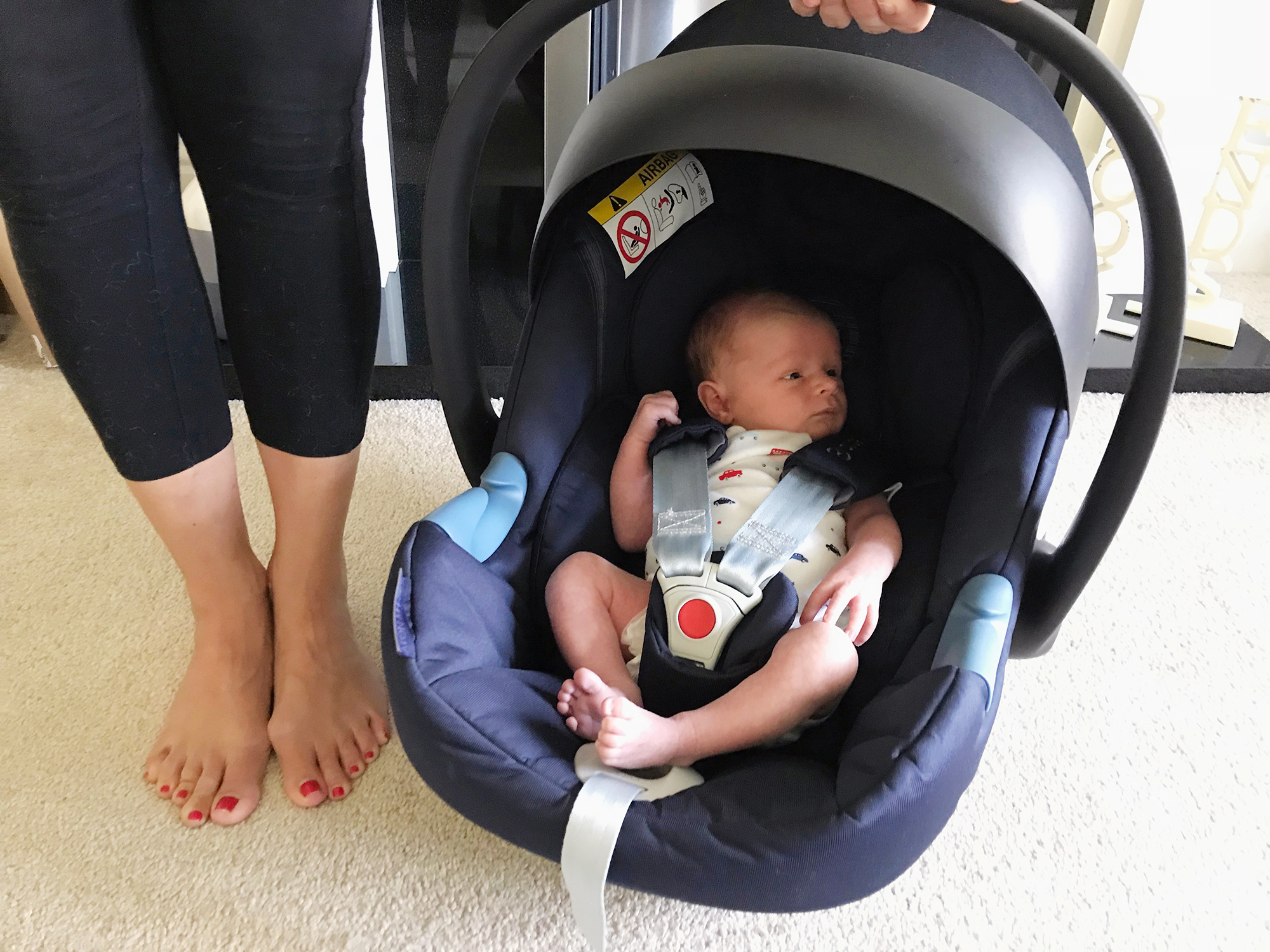 A newborn baby in a Cybex infant carrier car seat