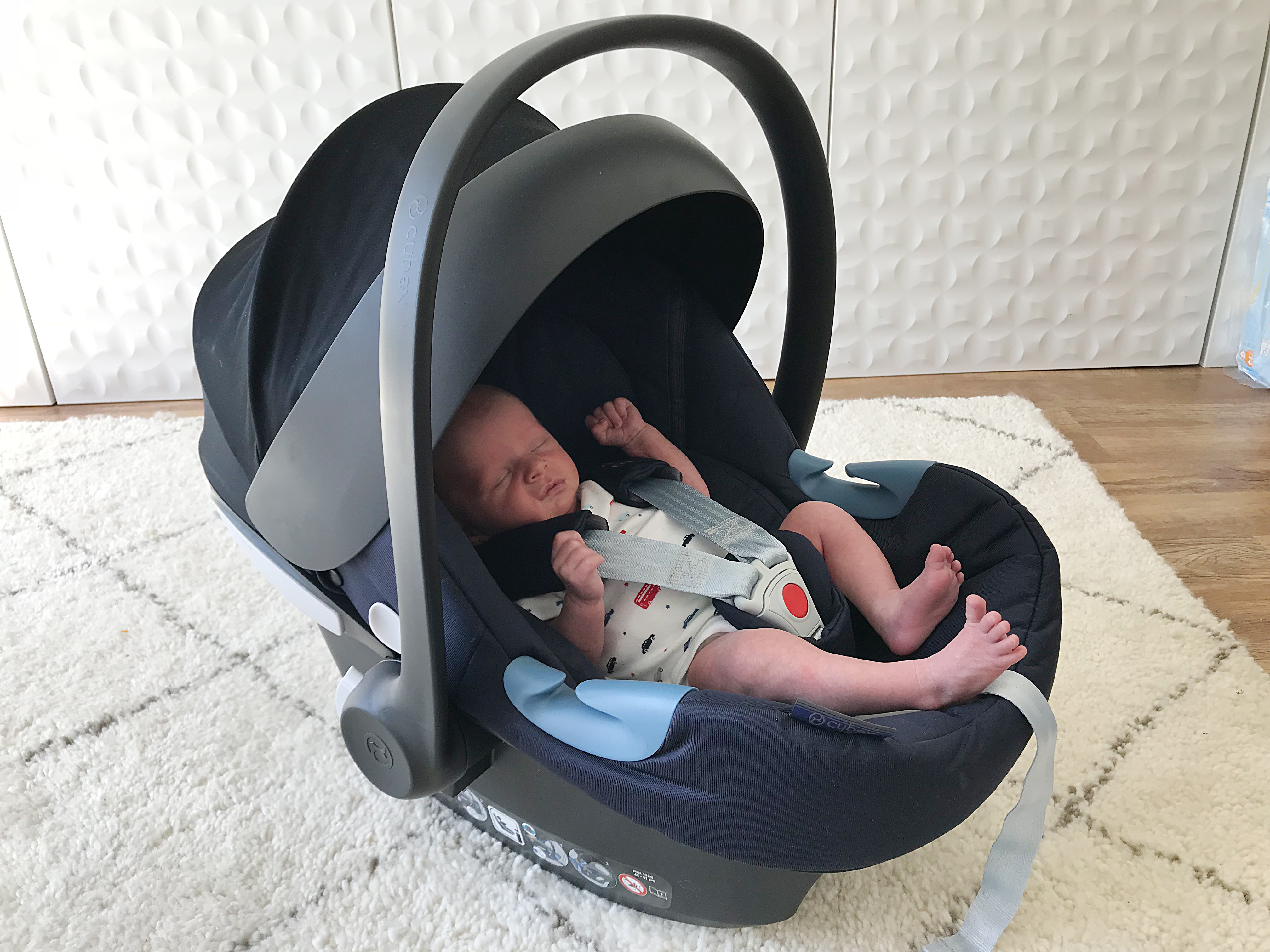 A newborn baby in a Cybex infant carrier car seat