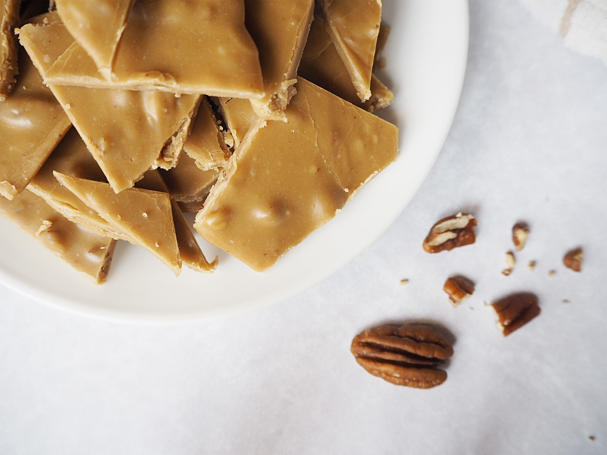 A plate of frosting bites next to some broken pecans