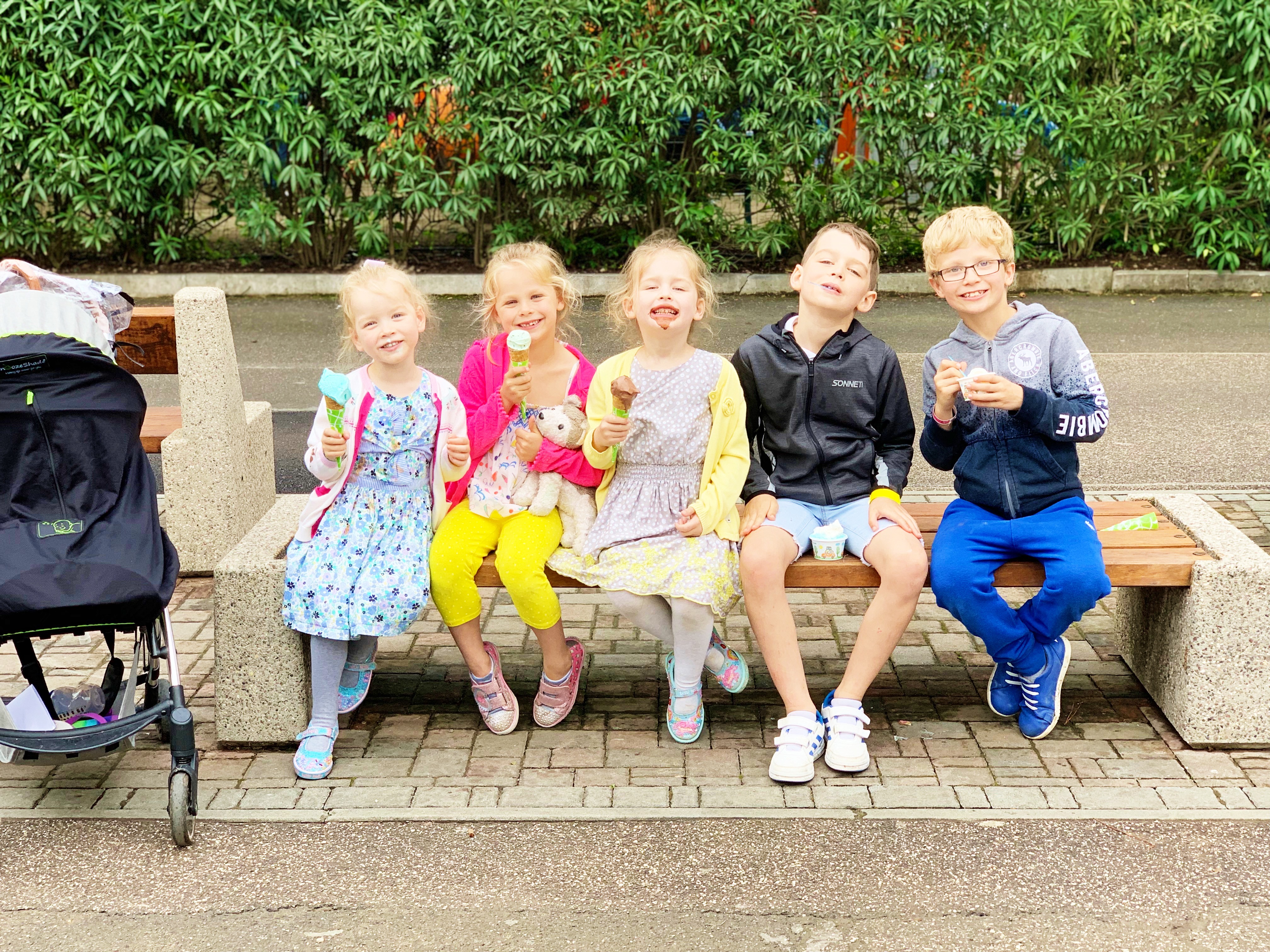 5 children sit on a bench with ice cream cones