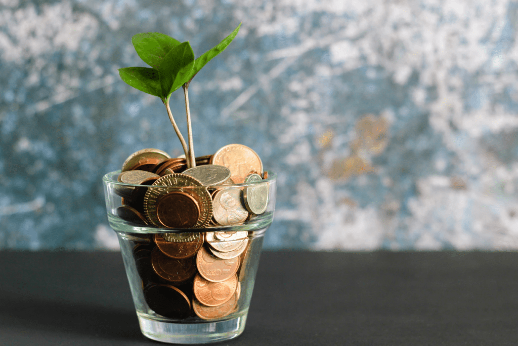 A glass full of coins with a small plant growing out the top