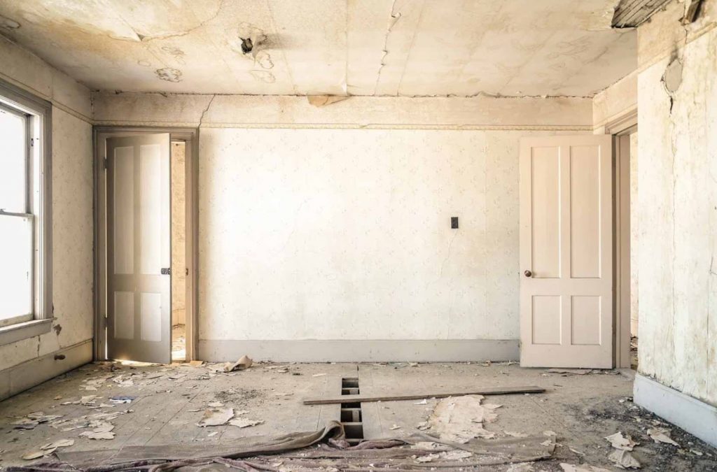 An empty dilapidated room with cream crumbling walls and ceiling