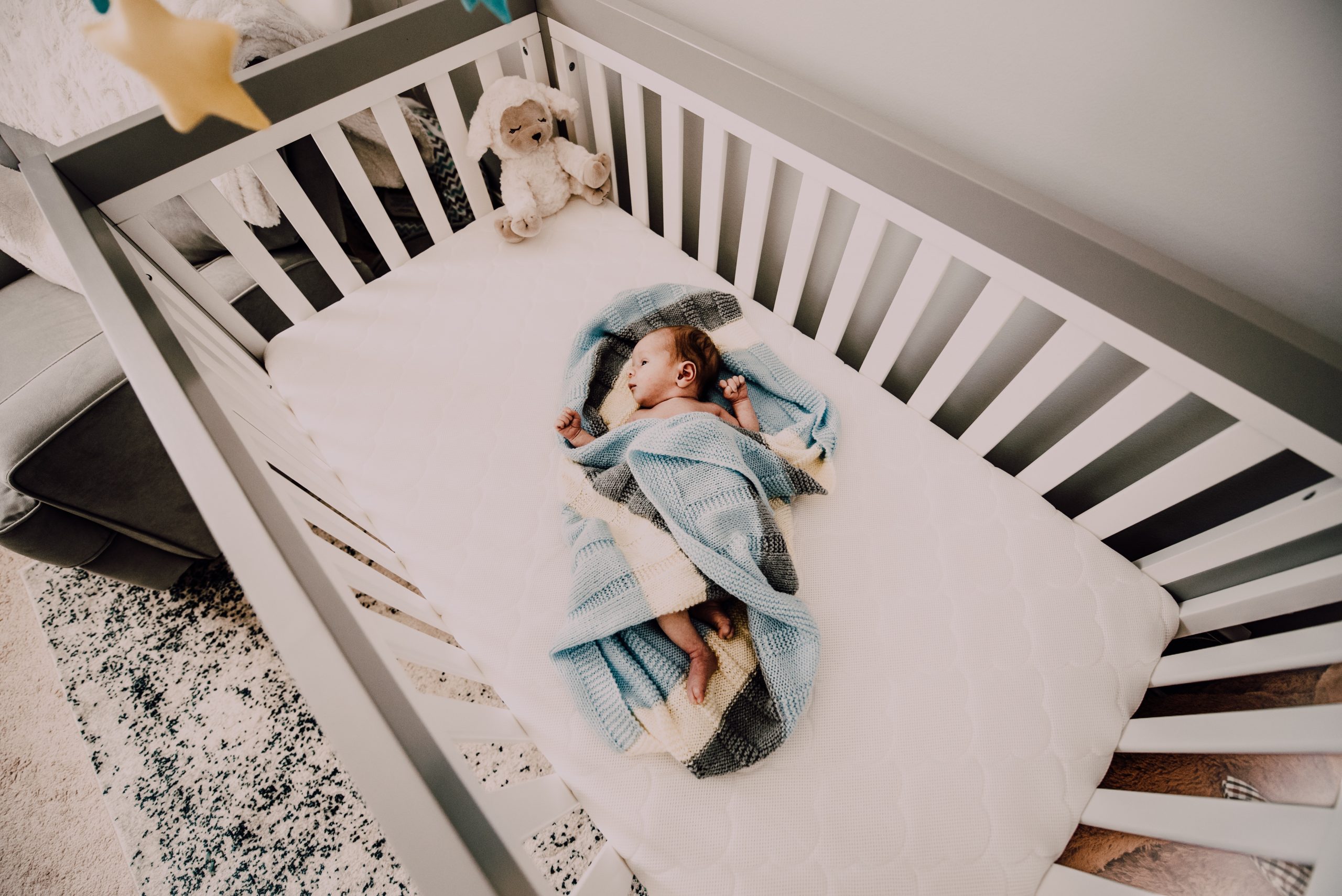 A baby wrapped in a blanket and lying in a crib