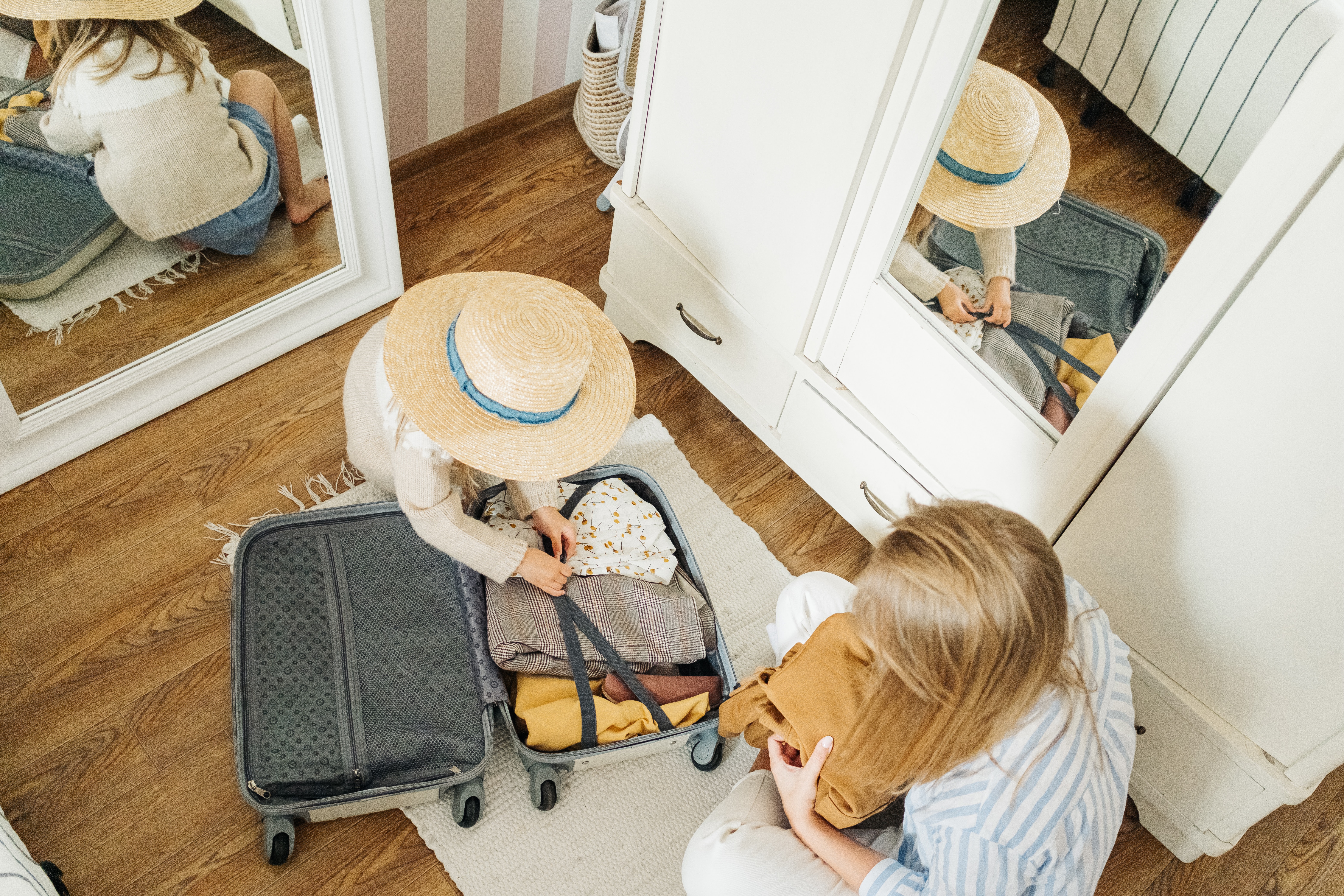 A mum and a child placing clothes into a small wheelie suitcase