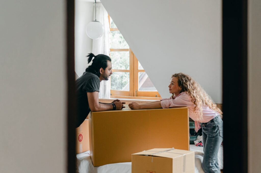 happy diverse couple opening carton boxes in new home