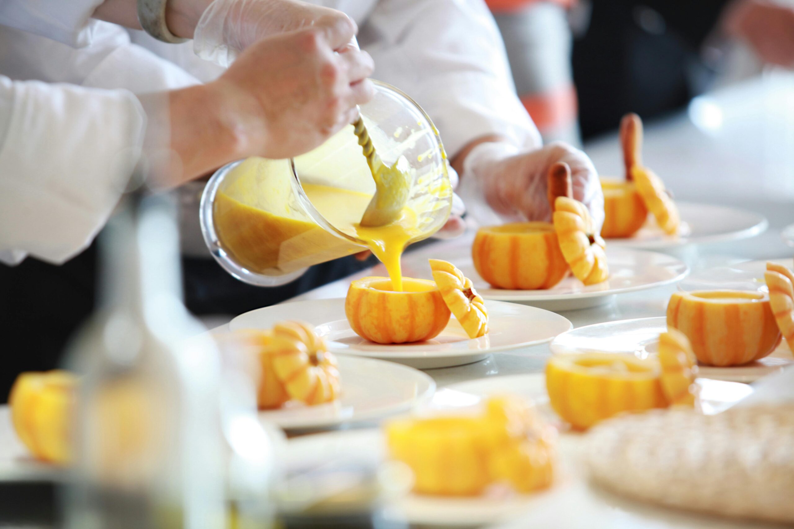 A group of Home Chefs showcasing their Culinary Entrepreneurship skills by scaling up their dishes with the addition of orange juice pouring onto plates of food.