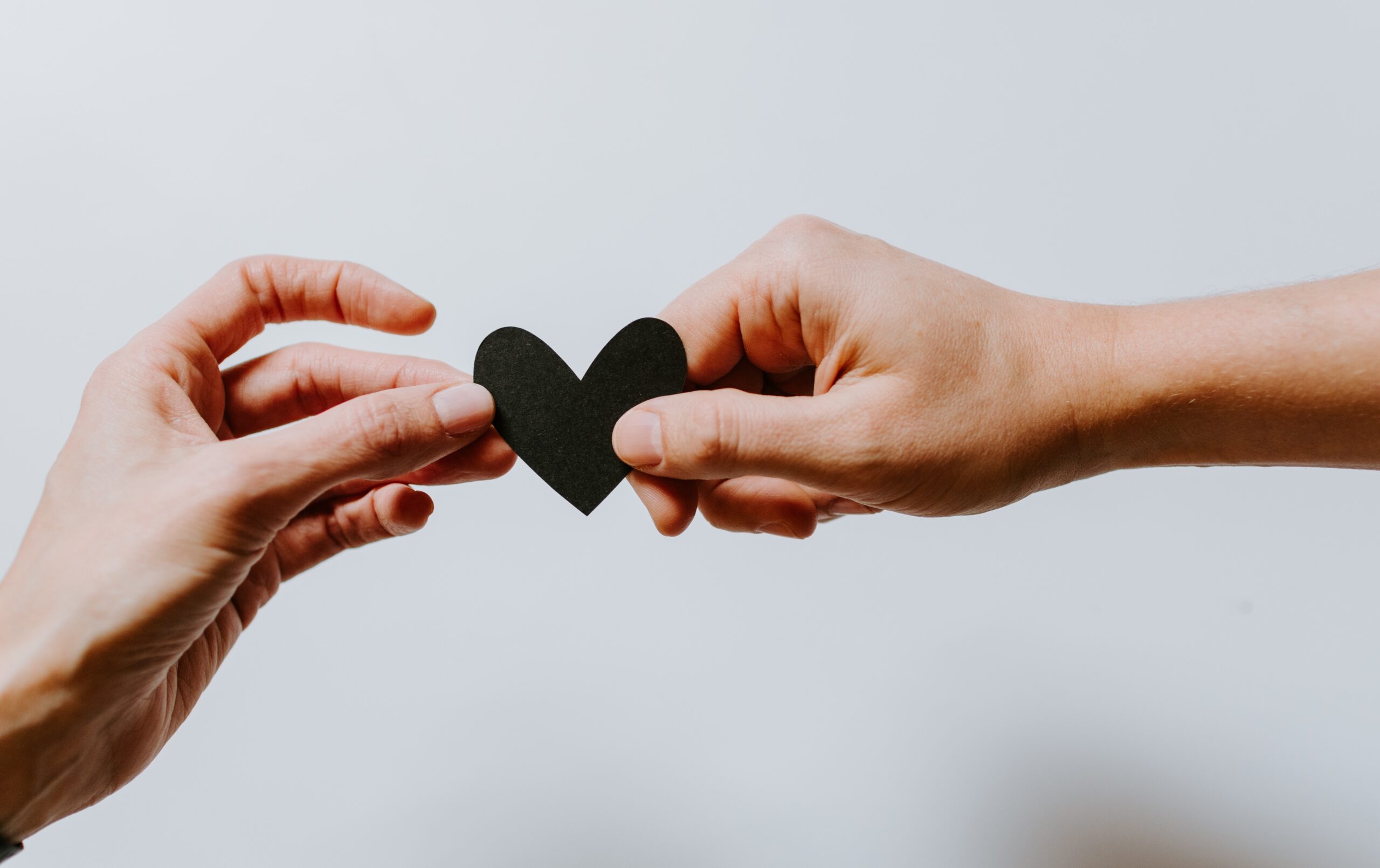 Two hands holding a black heart on a white background providing comprehensive family support during mesothelioma battles.