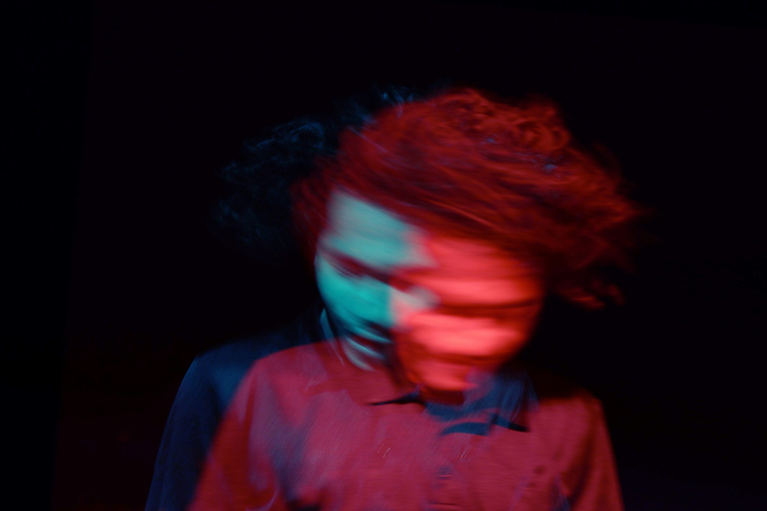 A blurry image of a person with curly hair.