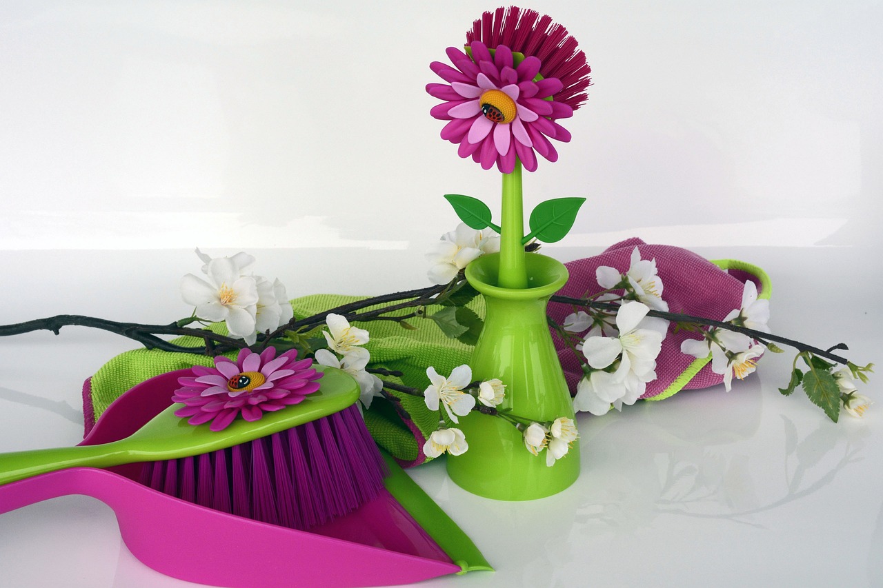 Colorful cleaning supplies arranged artistically with flowers on a white background.